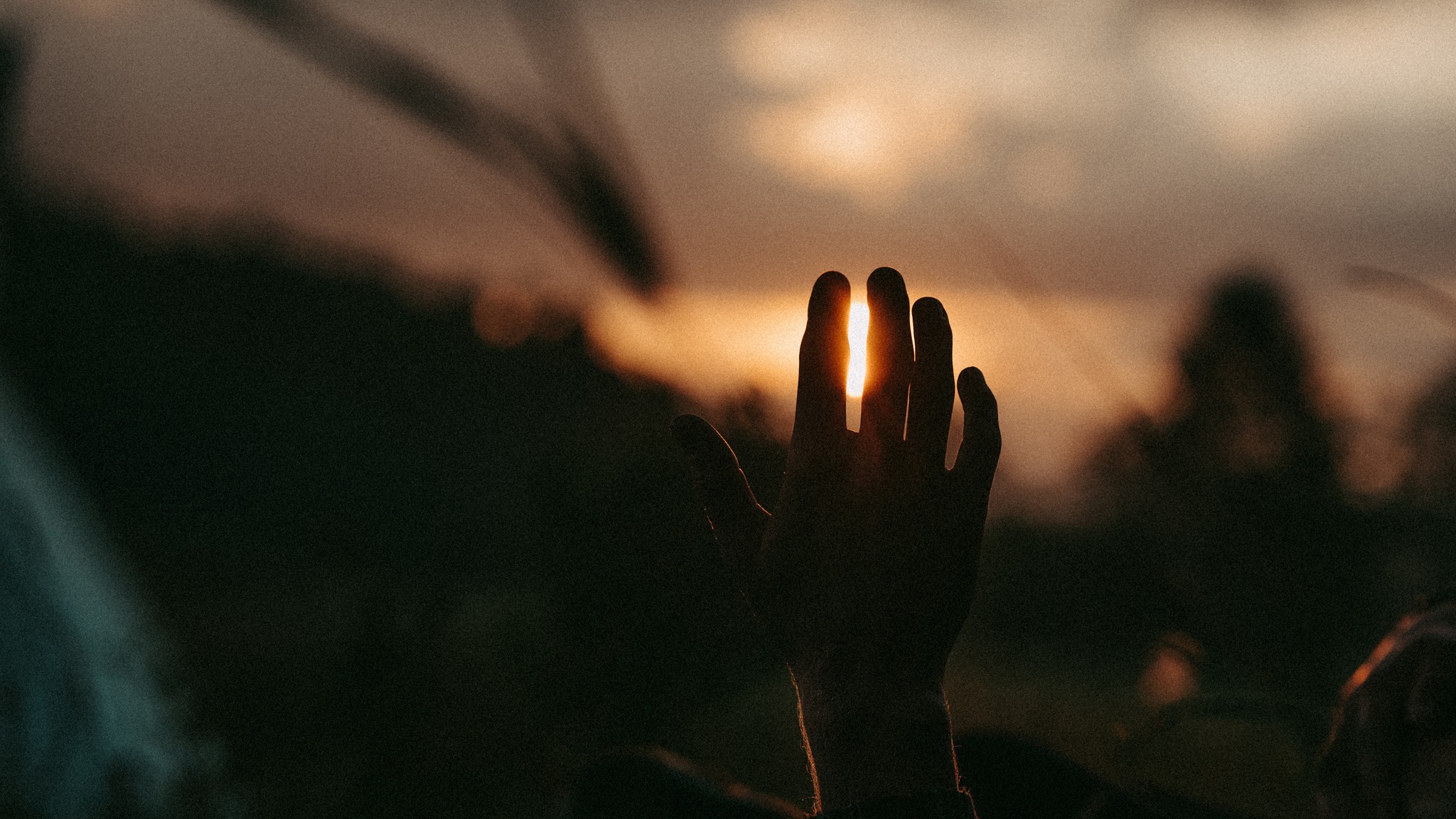 Hand reaching toward sunset